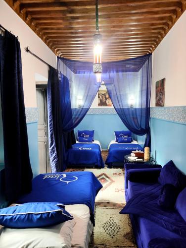 two beds in a room with blue curtains at Riad Ciel d'Orient in Marrakech