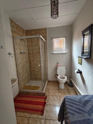 a bathroom with a shower and a toilet at Martinique Guesthouse in Kathu