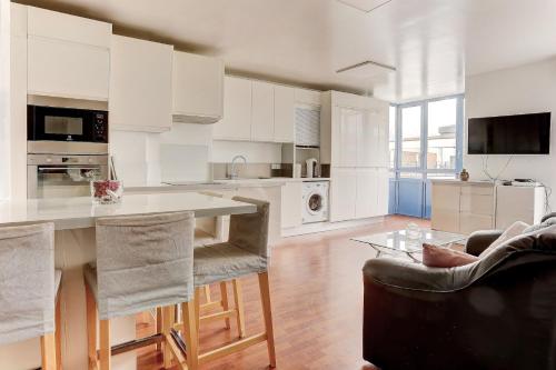 une cuisine avec des armoires blanches et une table et des chaises dans l'établissement La perle de sully - mante la jolie, à Mantes-la-Jolie