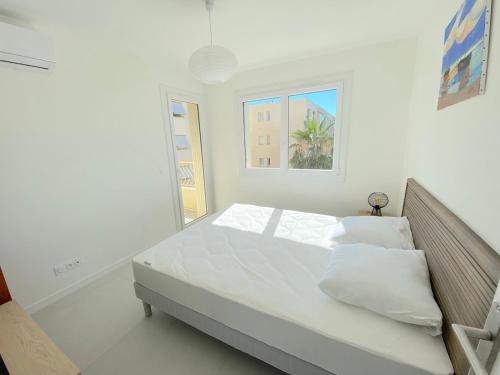 une chambre blanche avec un lit et une fenêtre dans l'établissement T3 - 5 min du Centre Ville et Plage - Parking, à Sanary-sur-Mer