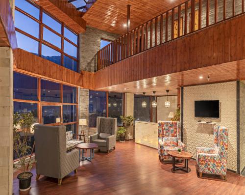 a large room with chairs and a television in it at Echor Himalayan Aurum Manali, Heating & Cooling in Manāli
