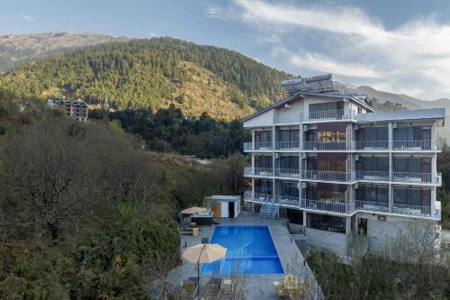 a large building with a swimming pool next to a mountain at Echor Himalayan Aurum Manali, Heating & Cooling in Manāli