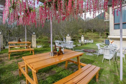 a picnic table and chairs under a pergola with pink flowers at Echor Himalayan Aurum Manali, Heating & Cooling in Manāli