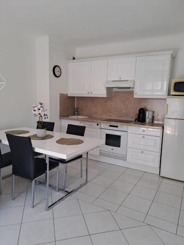une cuisine avec des armoires blanches et une table avec des chaises dans l'établissement Studio Cannes la Croisette, à Cannes