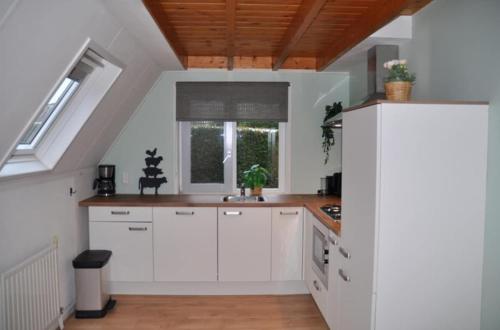 a kitchen with white cabinets and a window at Torenvalk I Genieten nabij Bos in Zwiggelte