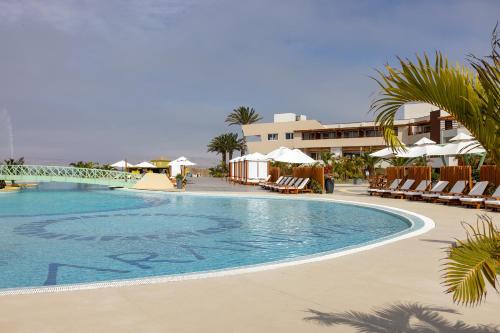 a pool at a resort with chairs and umbrellas at Aranwa Paracas Resort & Spa in Paracas