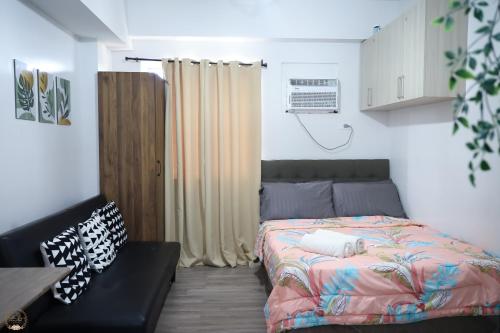 a small bedroom with a bed and a couch at Cozy Home in Cebu City