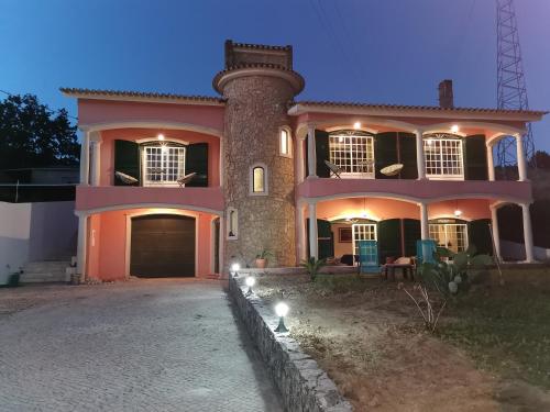 a large pink house with a tower at Casa Picamilho in Porto de Mós