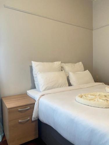 two beds with white pillows and a night stand at Wonderful Guest house in Durban