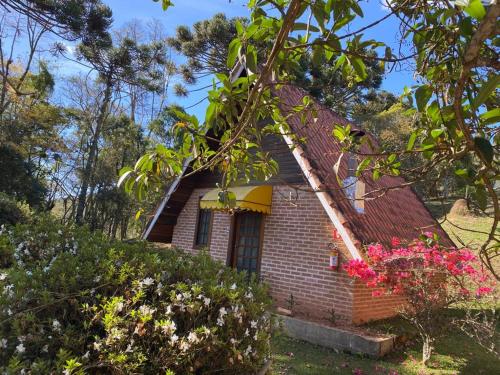 a small brick house with a window and flowers at Pousada Sotaque Mineiro in Cunha
