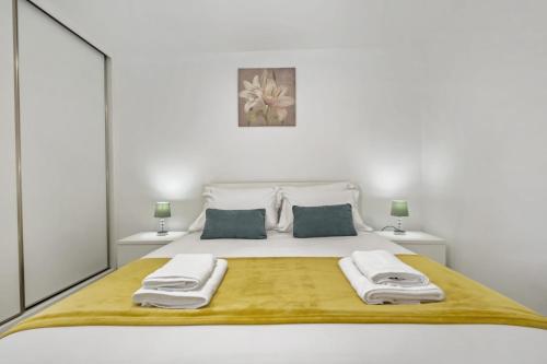 a white bedroom with a large bed with towels on it at Seaside Charm I in Câmara de Lobos