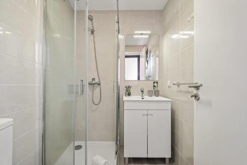 a white bathroom with a shower and a sink at Seaside Charm I in Câmara de Lobos