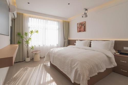 a bedroom with a white bed and a window at 一花一树音影民宿Tian Men mountian Branch in Wangjiazhai