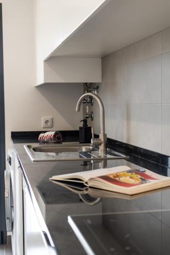 a kitchen with a sink with a book on it at Mar T2 - By Smarthomes in São Martinho do Porto