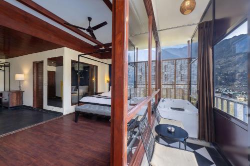 a bedroom with a bed and a tub and a balcony at Echor Himalayan Aurum Manali, Heating & Cooling in Manāli