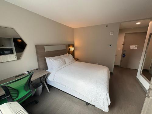 a bedroom with a bed and a desk with a computer at Holiday Inn Express & Suites Bronx - Zoo Area by IHG in Bronx