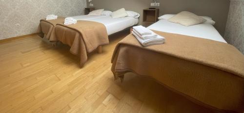 two beds in a room with wooden floors at Pension 23-Vinte e Tres in O Pedrouzo