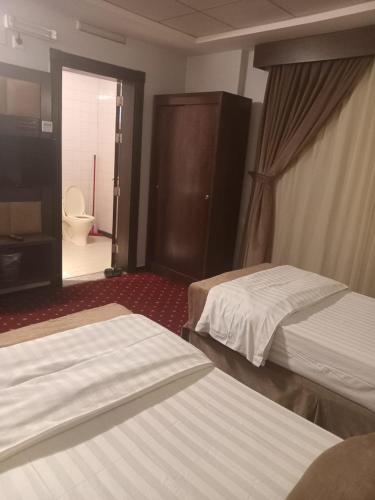a hotel room with two beds and a bathroom at شقق زهرة الباهية للشقق المخدومة in Najran