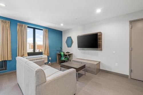 a living room with a couch and a tv at Holiday Inn Express & Suites Bronx - Zoo Area by IHG in Bronx