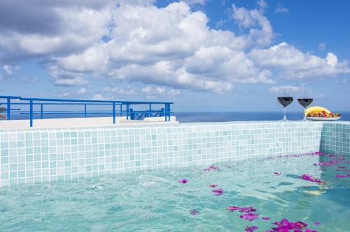 a swimming pool with wine glasses and flowers in the water at Villa Erofili in Fira