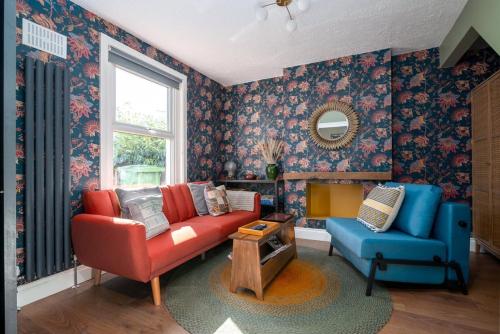 a living room with a red couch and a blue chair at Moonbeam Cottage - Cosy London Cottage in Eltham