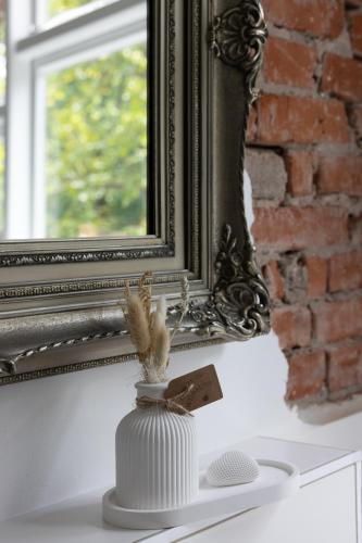 a white vase sitting on a table in front of a mirror at Oskar & Luise in Krummbek