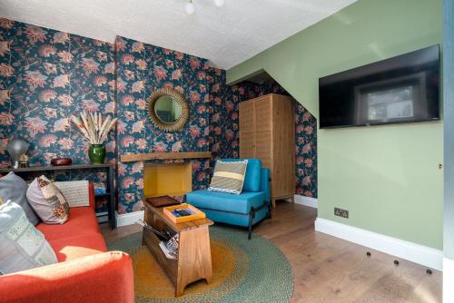 a living room with a blue couch and a tv at Moonbeam Cottage - Cosy London Cottage in Eltham
