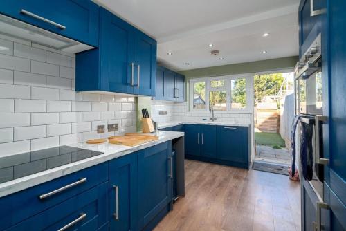a kitchen with blue cabinets and white tiles at Moonbeam Cottage - Cosy London Cottage in Eltham