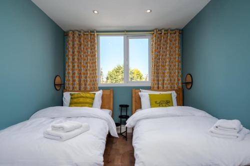 two twin beds in a room with a window at Moonbeam Cottage - Cosy London Cottage in Eltham
