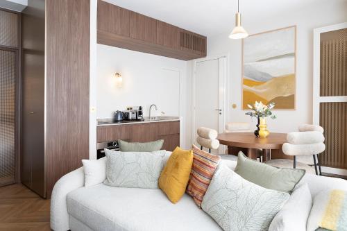 - un salon avec un canapé blanc et des oreillers colorés dans l'établissement Oniri - Serviced Apartments Eiffel Tower - rue d'Augereau, à Paris