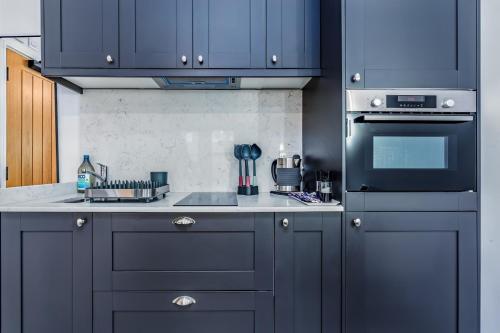 a kitchen with blue cabinets and a stove top oven at Cosy studio with parking and underfloor heating in Bristol