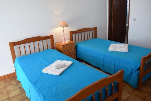アルブフェイラにあるVila Praia Apartmentの青いシーツとタオルが備わる客室内のベッド2台