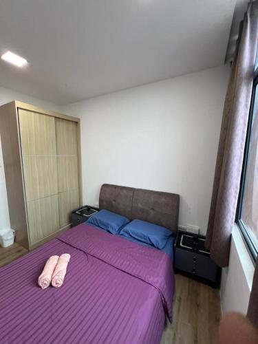 a bedroom with a purple bed with two slippers on it at Jin Lin Homestay 1 in Sibu