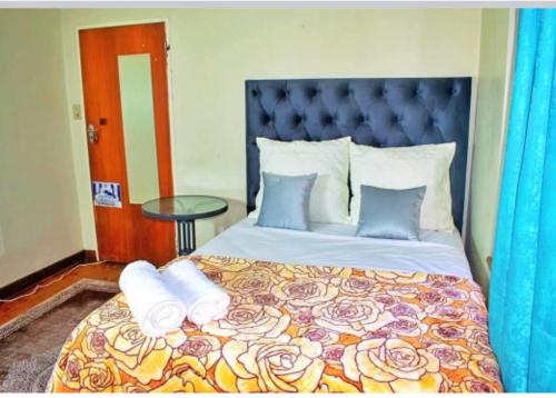 a bedroom with a large bed with a blue headboard at RMK Guest house Zeerust in Zeerust