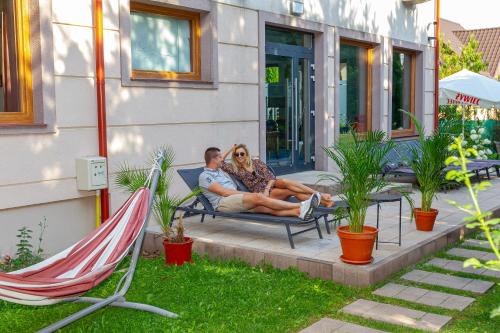 a man and woman sitting on a bench in a yard at Medical Spa Kwiatowa in Łęczyca