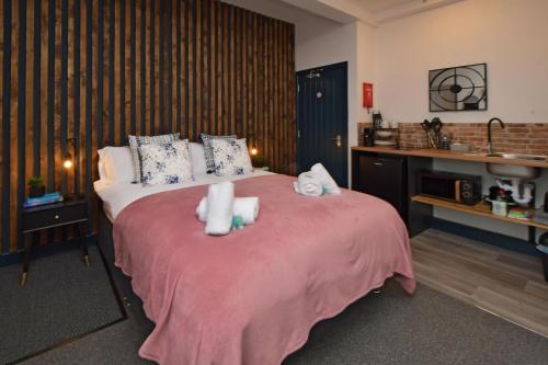 a bedroom with a pink bed with towels on it at Stay at Shobnall Road Rooms and Studios Burton in Burton upon Trent