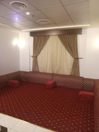 a waiting room with a red couch and a curtain at شقق زهرة الباهية للشقق المخدومة in Najran