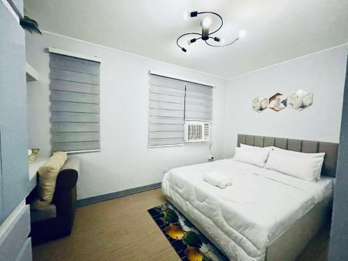 a white bedroom with a bed and a chair at RomgelTransientHouseFamily in Abucay