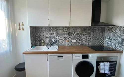a kitchen with a washing machine and a sink at L'écrin vert - Wifi - Netflix - Climatisation - Parking Gratuit in Périgueux