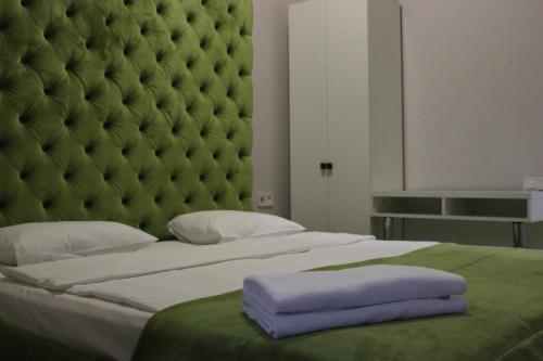 a bedroom with a large bed with a green headboard at De Paris Hotel in Kyiv