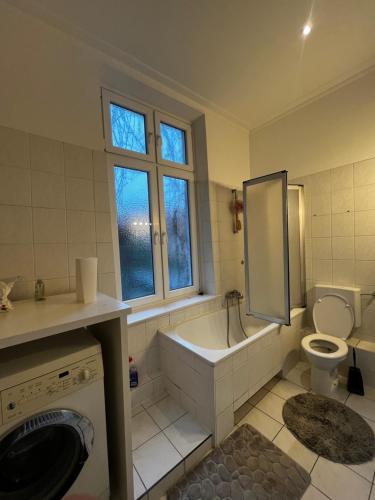 a bathroom with a tub and a toilet and a window at Idyllische Altbauwohnung mit vielen Schlafmöglichkeiten in Rendsburg