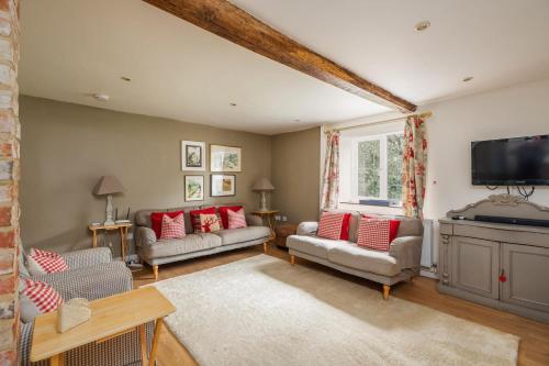 a living room with two couches and a flat screen tv at 18th Century Cottage in Dorset Countryside in Horton