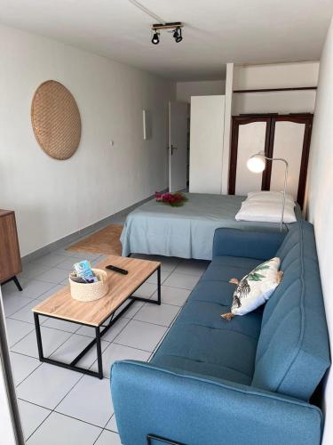 un soggiorno con un divano blu e un letto di Studio Saint Gilles les Bains a Saint-Gilles-les Bains