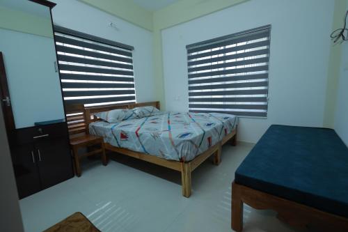 a bedroom with a bed and two large windows at Kailasam Residency in Trivandrum