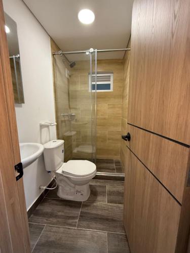 a bathroom with a toilet and a glass shower at Moravia Coliving in Bogotá