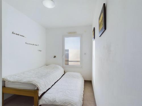 deux lits dans une chambre avec une fenêtre dans l'établissement À 50m de la plage, appartement pour 6, vue mer, à La Tranche-sur-Mer