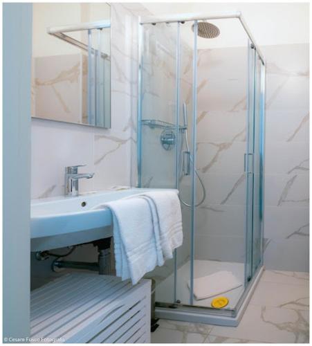 a bathroom with a glass shower and a sink at Hotel Caraibi - Breakfast Until 11-00 and Dinner-Mirabilandia Partner in Milano Marittima