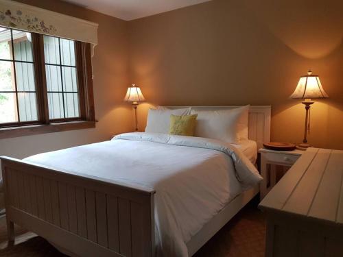 Un dormitorio con una gran cama blanca con dos lámparas. en Luxury Mountain Escape- Equinoxe 140-1, en Mont-Tremblant