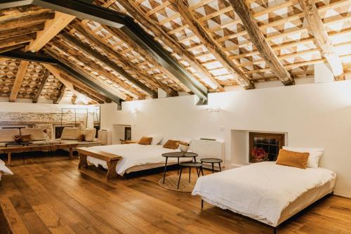 two beds in a large room with wooden ceilings at Vila Kobdilj 1835 - Unique Stay in Karst Stone Villa in Štanjel
