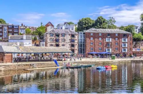 a group of boats in a body of water with buildings at Charming character lodge in cemetery grounds in Exeter